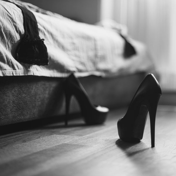 high heeled shoes next to bed with clothing scattered